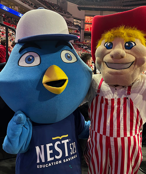 Nester and the Cornhusker mascot standing in a basketball arena.